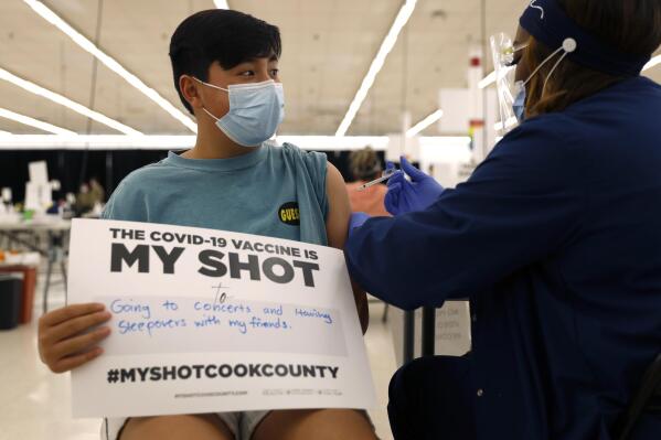 FILE - Lucas Kittikamron-Mora, 13, holds a sign in support of COVID-19 vaccinations as he receives his first Pfizer vaccination at the Cook County Public Health Department, May 13, 2021 in Des Plaines, Ill. The U.S. is expanding COVID-19 boosters as it confronts the omicron surge, with the Food and Drug Administration allowing extra Pfizer shots for children as young as 12. Boosters already are recommended for everyone 16 and older, and federal regulators on Monday, Jan. 3, 2022 decided they’re also warranted for 12- to 15-year-olds once enough time has passed since their last dose. (AP Photo/Shafkat Anowar, file)