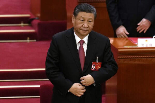 Chinese President Xi Jinping adjusts his jacket as he stands to sing the national anthem at the closing session of the National People's Congress held at the Great Hall of the People in Beijing, Monday, March 11, 2024. (AP Photo/Ng Han Guan)