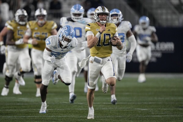 Georgia Tech quarterback Haynes King (10) runs for a big gain as North Carolina defensive back Giovanni Biggers (27) gives chase during the second half of an NCAA college football game, Saturday, Oct. 28, 2023, in Atlanta. (AP Photo/John Bzemore)