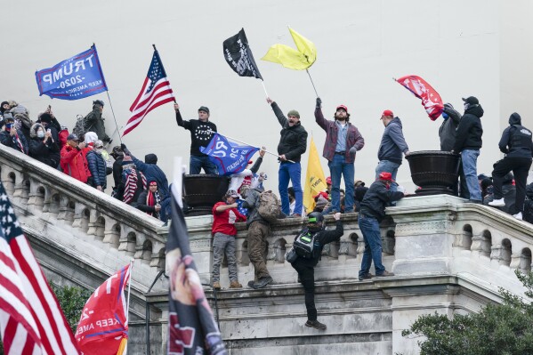 FILE - Rioters wave flags on the West Front of the U.S. Capitol in Washington on Jan. 6, 2021. Federal prosecutors say a network of supporters has helped fugitives from Florida avoid capture to face charges stemming from the riot. Prosecutors argued Thursday, March 14, 2024, that a Jan. 6 defendant, Thomas Osborne, is a flight risk because he is close to the family of a brother and sister from Lakeland, Fla. who remained on the run for months after they were charged with storming the Capitol. (AP Photo/Jose Luis Magana, File)
