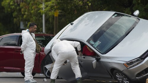 Forensic medical examiners work at the scene where an unidentified man was killed in Apatzingan, Mexico, Sunday, July 2, 2023. According to the victims, gunmen carjacked and, took their auto at gunpoint and used it to shoot another driver to death just a few blocks away. (AP Photo/Eduardo Verdugo)