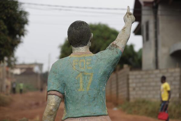 A man walks past the statue of late Cameroonian soccer star Marc-Vivien Foé, outside his abandoned soccer academy in Yaounde, Cameroon, Wednesday Feb. 2, 2022. The late Cameroon and Manchester City soccer star Marc-Vivien Foé had a dream to build a sports complex and school in his hometown of Yaounde. He never got to finish it after collapsing on a field while playing for his country in 2003 and dying of a heart condition at the age of 28. (AP Photo/Sunday Alamba)