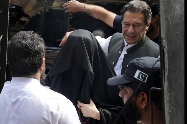 FILE - Pakistan's former Prime Minister Imran Khan, right, with his wife Bushra Bibi, center, arrive to appear in a court in Lahore, Pakistan, on June 26, 2023. A Pakistani court on Wednesday, Wednesday, Jan. 31, 2024 sentenced former Prime Minister Khan and his wife Bibi to 14 years in prison for corruption, prison officials said, a day after another special court convicted Khan for leaking state secrets and gave him a 10-year prison sentence. (AP Photo/K.M. Chaudary, File)