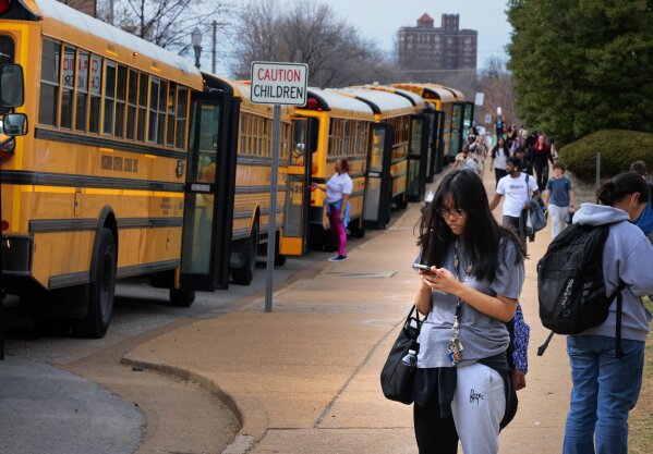 FILE - Metro High School students leave the building as a fleet of Missouri Central school busses line up to transport some after dismissal, Tuesday, Feb. 27, 2024, in St. Louis, Mo. Missouri Central School Bus Co. will end its contract with St. Louis Public Schools, Tuesday, March 26, a year early, bringing an end to a relationship strained after a bus driver “sickout” prompted by a noose left at the workstation of a Black mechanic in February(Christian Gooden/St. Louis Post-Dispatch via AP)