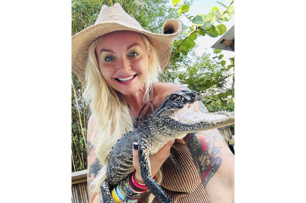 This photo posted on the Gatorland Facebook page on Saturday, Sept. 16, 2023 shows Savannah Boan, Crocodilian Enrichment Coordinator at the Gatorland theme park in Orlando, Fla., holding an alligator with a missing upper jaw that was that was rescued and brought to the park to be cared for. (Gatorland Facebook.com via AP)