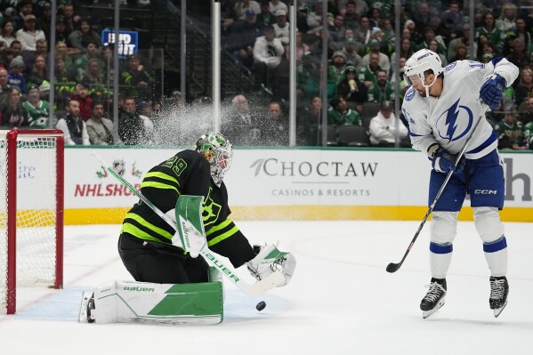 Dallas Stars goaltender Jake Oettinger, left, makes a save against Tampa Bay Lightning center Luke Glendening (11) during the second period of an NHL hockey game, Saturday, Dec. 2, 2023, in Dallas. (AP Photo/Julio Cortez)