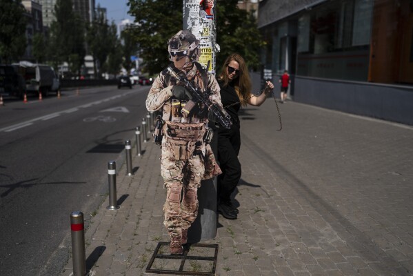 FILE - A store associate props the cutout of a soldier against a light pole outside a military surplus store in Kyiv, Ukraine, Thursday, July 6, 2023. (AP Photo/Jae C. Hong, File)