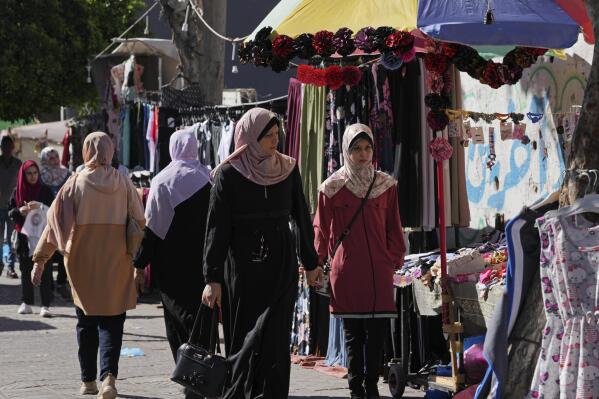 Women shop for clothes on the main road of an outdoor clothes market in Gaza City, Monday, July 25, 2022. Gaza’s Hamas rulers have imposed a slew of new taxes on imported clothes and school supplies just ahead of the new school year, sparking limited but rare protests in the impoverished coastal area. (AP Photo/Adel Hana)