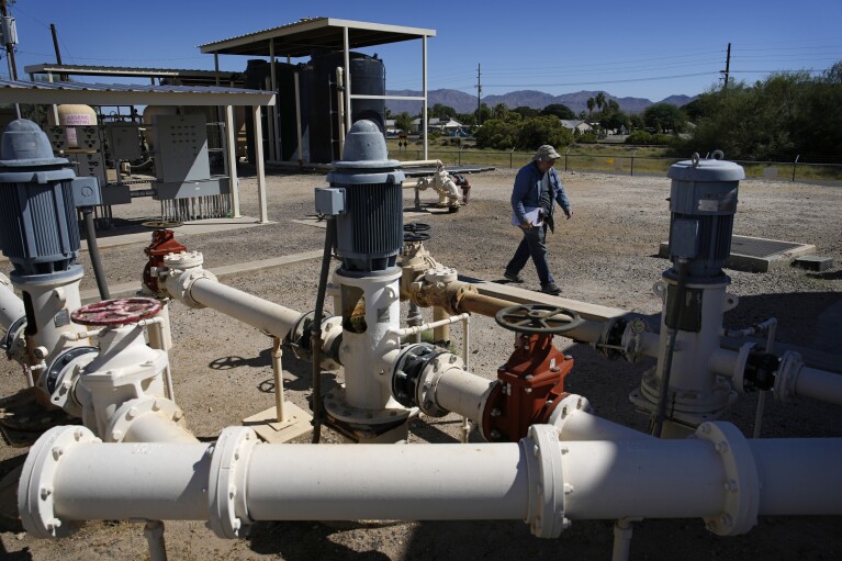 Water operator Robert Tipton walks by well equipment as he checks flow rates at the Wenden Domestic Water Improvement District's offices Tuesday, Oct. 17, 2023, in Wenden, Ariz. (AP Photo/John Locher)