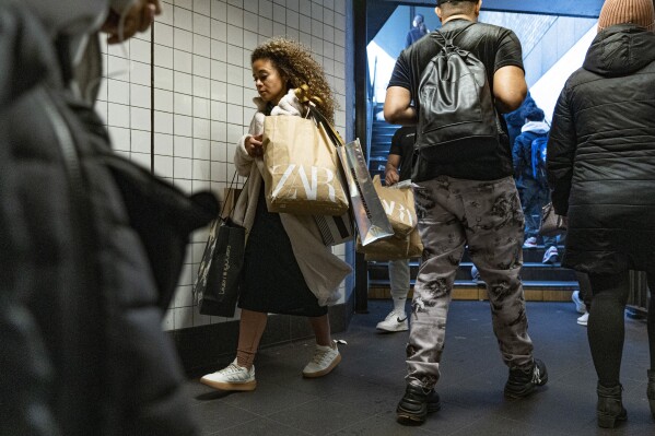 File - A woman holding several shopping bags enters a subway station on Black Friday, Nov. 24, 2023, in New York. On Tuesday, the Labor Department issues its report on inflation at the consumer level in November. (AP Photo/Peter K. Afriyie, File)