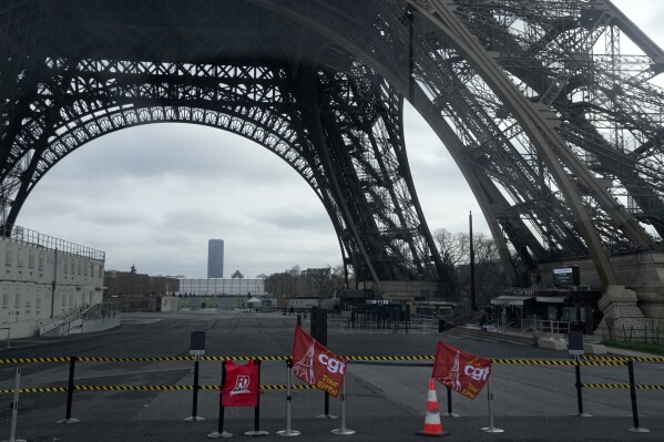 Unions flags are pictured at the Eiffel Tower, Tuesday, Feb. 20, 2024 in Paris. Visitors to the Eiffel Tower were turned away for the second consecutive day because of a strike over poor financial management at one of the world's most-visited sites. (AP Photo/Michel Euler)