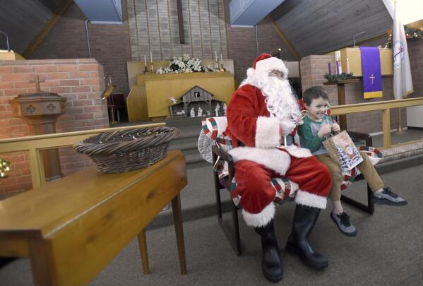 Walker Baker, 5, of Hagerstown, Md., visits with Santa Claus, portrayed by volunteer Wayne Hutzell, of Williamsport, Md., during Prison Fellowship's Angel Tree event for children of the incarcerated, Sunday Dec. 19, 2021 at Hub City Vineyard church in Hagerstown.  The Prison Fellowship's Angel Tree is expected to deliver gifts to about 300,000 kids nationwide this year. (AP Photo/Steve Ruark)