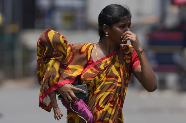 A woman covers a child using a part of her sari to shield from the sun on a hot summer day in Hyderabad, India, Tuesday, April 30, 2024. (Ǻ Photo/Mahesh Kumar A.)
