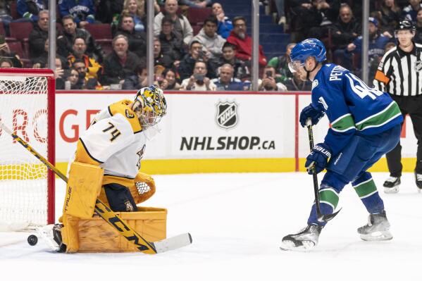 Vancouver Canucks' Elias Pettersson, right, scores on Nashville Predators goalie Juuse Saros during the shootout in an NHL hockey game in Vancouver, British Columbia, Monday, March 6, 2023. The Canucks defeated the Predators 4-3. (Rich Lam/The Canadian Press via AP)