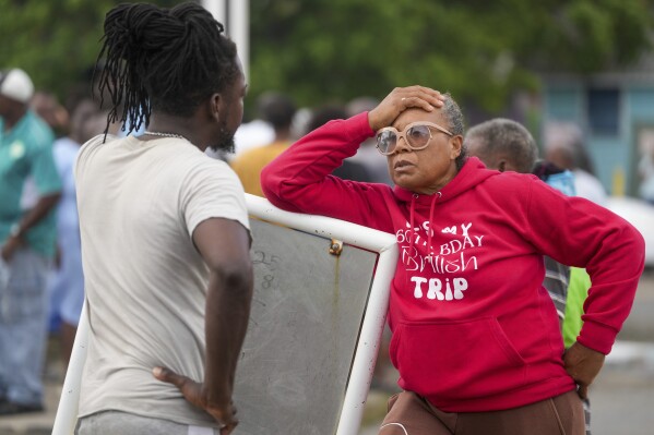 Sylvia Small, right, waits for police approval to enter the pier to check her boat's damages due to Hurricane Beryl at the Bridgetown Fisheries in Barbados, Monday, July 1, 2024. (AP Photo/Ricardo Mazalan)