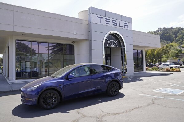 Two women in an electric car drive into a Tesla delivery location and service center Friday, April 2, 2021, in Corte Madera, Calif. The president and auto industry maintain the nation is on the cusp of a gigantic shift to electric vehicles and away from liquid-fueled cars, but biofuels producers and some of their supporters in Congress aren't buying it and argue now is the time to increase sales of ethanol and biodiesel, not abandon them. (AP Photo/Eric Risberg)