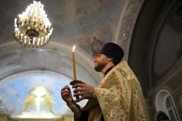 A Russian Orthodox Church priest makes the sign of the cross during an Orthodox Christmas service at the Church of the Holy Martyr Tatiana near the Kremlin Wall in Moscow, Russia, late Saturday, Jan. 6, 2024.  (AP Photo/Alexander Zemlianichenko)