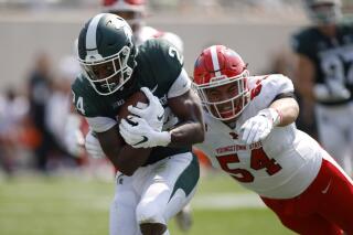 FILE - Michigan State running back Elijah Collins, left, runs for a touchdown against Youngstown State's Vinny Gentile (54) during the second quarter of an NCAA college football game Sept. 11, 2021, in East Lansing, Mich. Collins is among the candidates to fill the hole left by the departure of Kenneth Walker III. (AP Photo/Al Goldis, File)