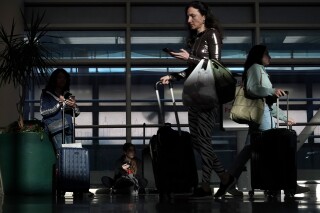 FILE - Commercial airline passengers wait, and make their way through the ticketing level at Chicago's Midway International Airport Friday, May 26, 2023, in Chicago. The Department of Transportation is investigating possible deceptive practices in airline loyalty programs after federal lawmakers raised concerns about how airlines are calculating points and rewards.(AP Photo/Charles Rex Arbogast, File)