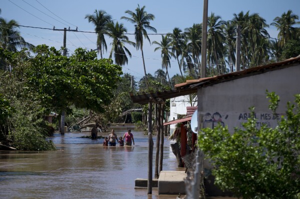 FILE - Residents wade down a street through receding floodwaters, two days after Hurricane Patricia, in the village of Rebalse, Jalisco State, Mexico, Oct. 25, 2015. A handful of powerful tropical storms in the last decade and the prospect of more to come has some experts proposing a new category of hurricanes: Category 6, which would be for storms with wind speeds of 192 miles per hour or more. (AP Photo/Rebecca Blackwell, File)