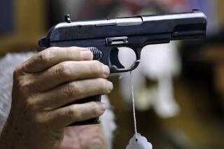 FILE - A sales clerk holds a pistol during an auction in Rochester, Wash., on Oct. 20, 2017. A study published in Annals of Internal Medicine on Monday, April 4, 2022, suggests people who live with handgun owners are murdered at more than twice the rate of people who live in homes without such firearms. (AP Photo/Elaine Thompson, File)
