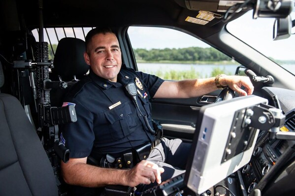 In this 2019 photo provided by the Dighton Police Department, Dighton officer Shawn Cronin sits at the wheel of a police vehicle, in Dighton, Mass. Officials say Cronin, who rose up the ranks to become Dighton Police Chief, is charged with insider trading that allegedly netted a group of men more than $2.2 million in illegal profits. Cronin, who is to resign, is among five men charged in the insider trading scheme. (Dighton Police Department via AP)