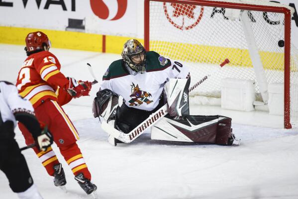Arizona Coyotes goalie Karel Vejmelka, right, lets in a goal from Calgary Flames' Johnny Gaudreau during second-period NHL hockey game action in Calgary, Alberta, Friday, March 25, 2022. (Jeff McIntosh/The Canadian Press via AP)
