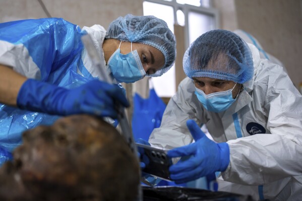 Forensic workers at a morgue in Kyiv, Ukraine, examine the body of a Ukrainian prisoner of war returned by Russia, June 24, 2024. (AP Photo/Alex Babenko)