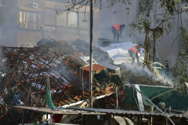 In this photo released by the official Syrian state news agency SANA, emergency service workers clear the rubble at a destroyed building struck by Israeli jets in Damascus, Syria, Monday, April 1, 2024. An Israeli airstrike has destroyed the consular section of Iran's embassy in Syria, killing a senior Iranian military adviser and roughly a handful of other people, Syrian state media said Monday. (SANA via AP)