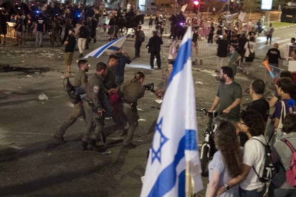 Israeli police remove a person protesting against Israeli Prime Minister Benjamin Netanyahu's government as demonstrators call for the release of hostages held in the Gaza Strip by the Hamas militant group, in Tel Aviv, Israel, Saturday, June 1, 2024. (AP Photo/Maya Alleruzzo)