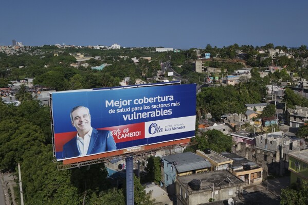 A political billboard with a message that reads in Spanish: "Better health coverage for the most vulnerable sectors", promotes the candidacy of incumbent President Luis Abinader, who is running for reelection, in Santo Domingo, Dominican Republic, Thursday, May 16, 2024. (AP Photo/Matias Delacroix)