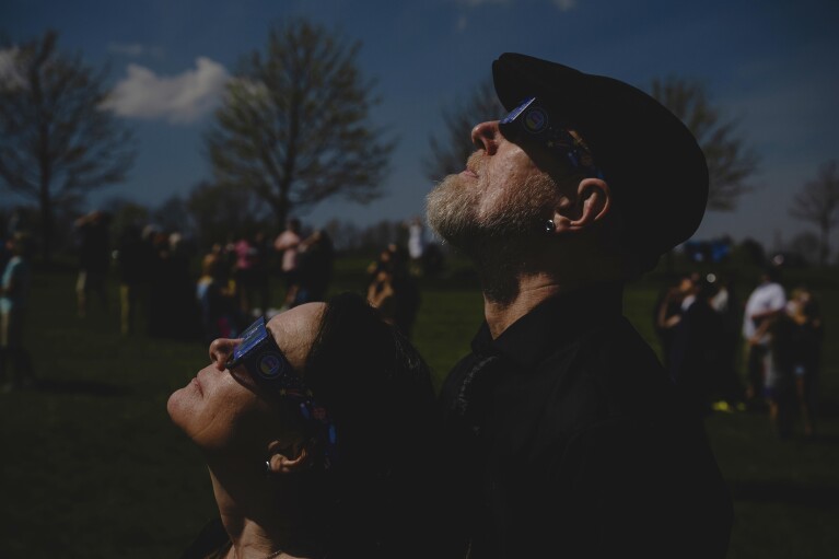 زوجان حديثا ينظران إلى كسوف كلي للشمس خلال حفل زفاف جماعي في حديقة ترينتون المجتمعية، الاثنين 8 أبريل 2024، في ترينتون، أوهايو. (صورة ا ف ب/جون شيري)