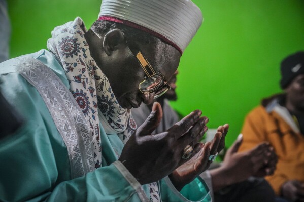 Imam Omar Niass leads evening prayers with mostly Senegalese migrants, before the breaking of Ramadan fast and the serving of a festive meal called an iftar, Friday March 15, 2024, at Bronx's Masjid Ansaru-Deen mosque in New York. The mosque, formerly the Imam's home, has been a refuge since 2020 where hundreds of African migrants can find help while seeking asylum in the United States. (AP Photo/Bebeto Matthews)