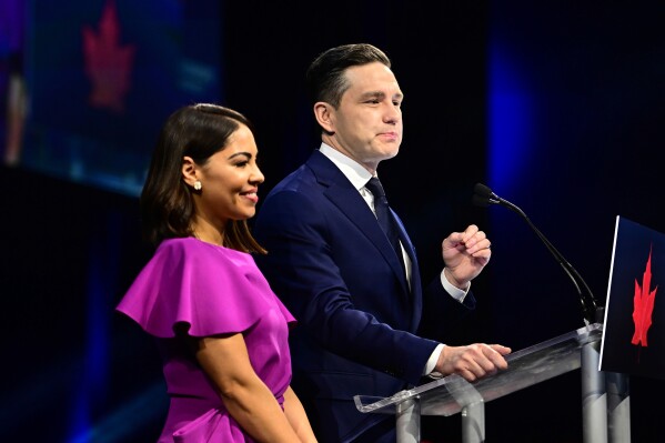 Conservative Leader Pierre Poilievre speaks to supporters with his wife Anaida Poilievre at his campaign headquarters on election night, in Ottawa, Tuesday, April 29, 2025. (Spencer Colby/The Canadian Press via AP)