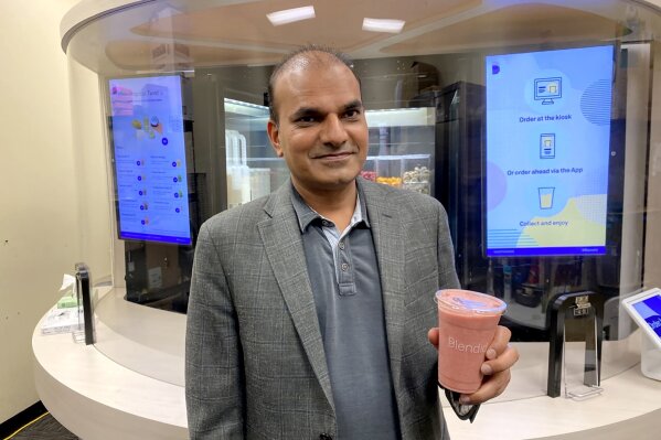 Vipin Jain, CEO and cofounder of Blendid, holds a smoothie on Tuesday, June 30, 2020, in Sunnyvale, Calif.,  made by his company’s robotic kiosk that makes blended fruit drinks with no human intervention. “I expect in the next two years you will see pretty significant robotic adoption in the food space because of COVID,” said Jain. 
 (AP Photo/Terry Chea)