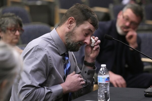 Sean Hodgson, a member of the U.S. Army Reserve, wipes tears while recalling the moment he heard about the mass shooting, Thursday, April 25, 2024, in Augusta, Maine, during a hearing of the independent commission investigating the law enforcement response to the mass shooting in Lewiston, Maine. (AP Photo/Robert F. Bukaty)