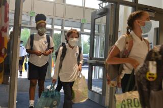 FILE - Students enter the first new Catholic school built in Baltimore in roughly 60 years on Monday, Aug. 30, 2021, named after Mother Mary Lange, who started a Catholic school for Black children in 1828 _ the first U.S. Catholic school for African-American youth. Enrollment in Roman Catholic schools in the United States rose 3.8% from the previous academic year, rebounding from a sharp drop caused by the coronavirus pandemic, Catholic education officials reported Monday, Feb. 14, 2022. (AP Photo/David McFadden)