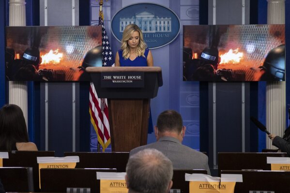 White House press secretary Kayleigh McEnany stands as a video from Portland, Ore., is shown during a press briefing in the James Brady Press Briefing Room at the White House, Friday, July 24, 2020, in Washington. (AP Photo/Alex Brandon)