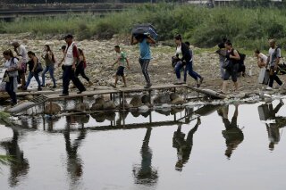 FILE - In this April 14, 2019 file photo, Venezuelans cross illegally into Colombia near the Simon Bolivar International Bridge, seen from La Parada near Cucuta, Colombia. President Ivan Duque said on Wednesday, Feb. 3, 2021, that Colombia needs greater cooperation from the international community to carry out a vaccination plan against COVID-19 for the estimated  million Venezuelan migrants without documents who are in the country, who are so far excluded from the new coronavirus vaccination plan. (AP Photo/Fernando Vergara, File)