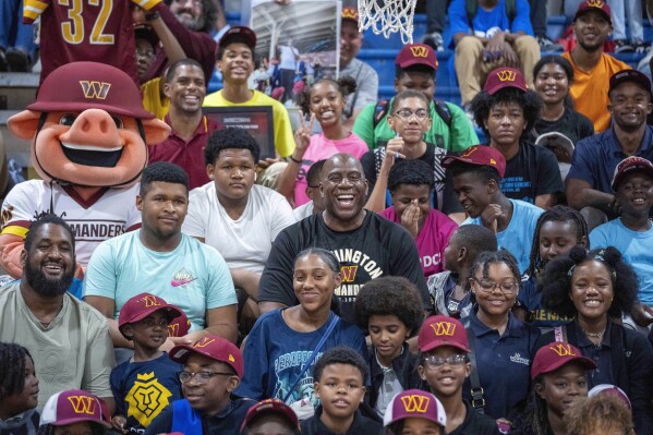 Washington Commanders part-owner Magic Johnson, center, poses for a photo in the stands with children at the Boys and Girls Club of Greater Washington, Thursday, Sept. 7, 2023, in Washington. (AP Photo/Alex Brandon)