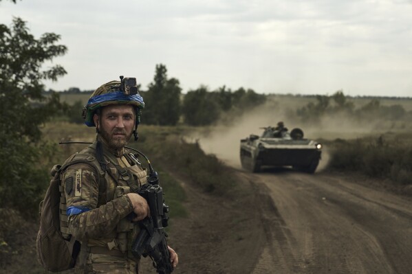 A soldier of Ukraine's 3rd Separate Assault Brigade looks on against the background of an APC near Bakhmut, the site of fierce battles with the Russian forces in the Donetsk region, Ukraine, Monday, Sept. 4, 2023. (AP Photo/Libkos)