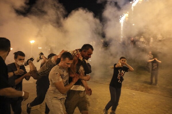Protesters carry a man injured during clashes with police amid anti-government demonstrations in Minsk, Belarus, Aug. 10, 2020. (AP Photo, File)