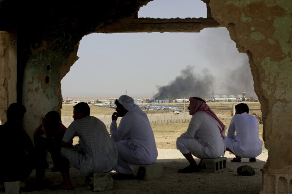 
              Jordanian residents of Jabir village watch aid deliveries to Syrians fleeing government offensive in the south as smoke from unknown fire rises, Tuesday, July 3, 2018. The UN says Syria government's Russian-backed offensive to recover southern territories from rebels has displaced 270,000 people, 60,000 of them headed near the sealed Jordanian borders.(AP Photo/Raad Adayleh)
            