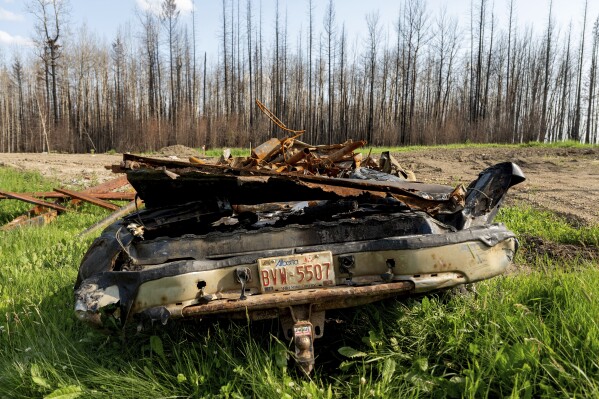 A scorched car rests in the yard of a home destroyed by a wildfire in the East Prairie Metis Settlement, Alberta, on Tuesday, July 4, 2023. The settlement, whose residents trace their ancestry to European and Indigenous people, lost at least 14 homes during the May wildfire, according to Chair Raymond Supernault. (AP Photo/Noah Berger)