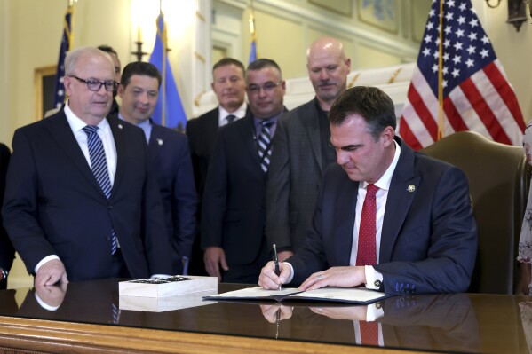Oklahoma Gov. Kevin Stitt signs an executive order in the Blue Room at the state Capitol in Oklahoma City, Wednesday, Dec. 13, 2023. In Oklahoma, Republican Gov. Kevin Stitt signed an executive order in December barring state agencies and universities from spending money diversity initiatives. (Sarah Phipps/The Oklahoman via AP)
