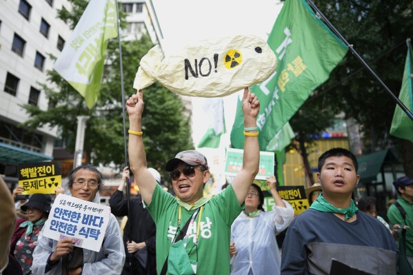 People hold banners and posters to protest Japan's plan to release treated radioactive water from the wrecked Fukushima nuclear power plant, during a match along a street in Seoul, South Korea, Saturday, Aug. 12, 2023. Anxious about Japan’s impending release of treated nuclear wastewater from the tsunami-damaged Fukushima power plant, hundreds of South Koreans marched in their capital on Saturday. (AP Photo/Lee Jin-man)