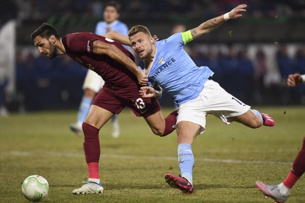 CFR's Denis Kolinger, left, challenges for the ball with Lazio's Ciro Immobile during the Europa Conference League playoff second leg soccer match between CFR Cluj and Lazio, at the Constantin Radulescu Stadium in Cluj, Romania, Thursday, Feb. 23, 2023. (AP Photo/ Raed Krishan)