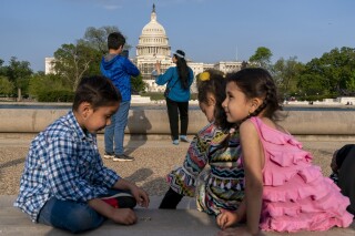 FILE - Members of the Safi family, who were evacuated from Afghanistan and are trying to make a new life in the U.S. while in immigration limbo, celebrate Eid by taking family photographs on the National Mall, May 3, 2022, near the U.S. Capitol in Washington. Growing opposition to the Senate border package once again poses a risk to the more than 76,000 Afghans who worked alongside U.S. soldiers in America’s longest war, and who are currently living in the U.S. in immigration uncertainty as a result of years of congressional inaction. (AP Photo/Jacquelyn Martin, File)