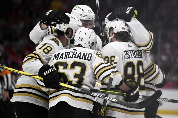 Boston Bruins left wing Brad Marchand (63), right wing David Pastrnak (88) and others celebrate a goal by defenseman Hampus Lindholm, back right, against the Washington Capitals during the first period of an NHL hockey game Saturday, March 30 2024, in Washington. (AP Photo/Nick Wass)