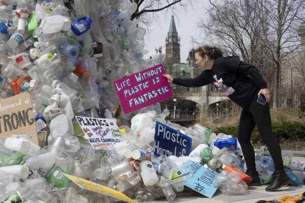 FILE - Activist Dianne Peterson places a sign on an art installation outside a United Nations conference on plastics, April 23, 2024, in Ottawa, Ontario. (Adrian Wyld/The Canadian Press via AP. File)